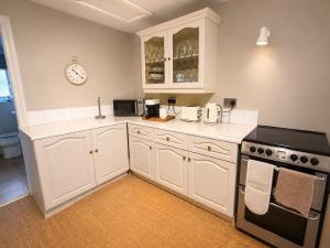 a kitchen with white cabinets and a clock on the wall at Paddock View Loft Countryside Retreat in Thornhill