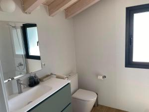 a bathroom with a sink and a toilet and a mirror at La Llarena in La Isla