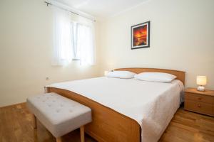 a white bedroom with a large bed with a chair at Blue Horizon Retreat in Trogir