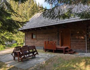 two benches sitting outside of a log cabin at Jariabka Chalet - sun terace, fireplace, grill, space to play, green embrace of the forest in the Low Tatras in Jarabá