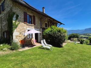 a house with two lawn chairs and an umbrella at Maison au calme en Chartreuse in Miribel-les-Échelles