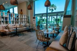 a restaurant with tables and chairs and large windows at Mercure Nador Rif in Nador