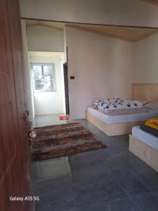 a bedroom with two beds and a window and a rug at Auli haven in Joshīmath