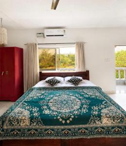 a bedroom with a bed with a green blanket on it at Bhumika by evaddo stays in Mandrem