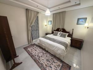 a bedroom with a large bed and a rug at شقق واحة المحمدية in Baljurashi