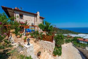 a house on a hill with the ocean in the background at Istlada Taş Ev Apart - Kekova Island View in Demre
