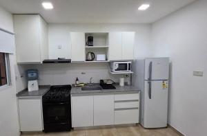 a small kitchen with white cabinets and a refrigerator at Moderno apartamento en Colón in Colón Buenos Aires Province