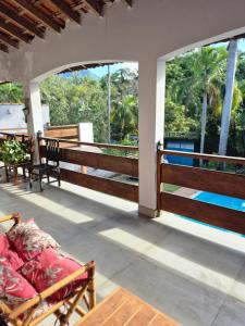 a porch with two chairs and a bed on it at Morada Palmeira Real Peruibe - SP in Peruíbe