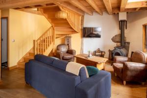 a living room with a blue couch and a staircase at The Dragon Barn - Grenier in Ascou
