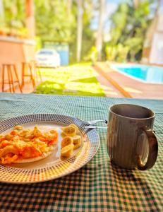 a plate of food and a cup of coffee on a table at Morada Palmeira Real Peruibe - SP in Peruíbe