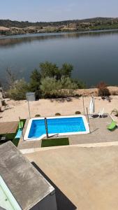 a swimming pool in front of a body of water at Iberfishing Apartmanok in Caspe