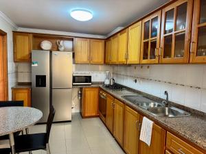 a kitchen with wooden cabinets and a stainless steel refrigerator at Cantinho de Santa Teresa in Canhas +3 photos
