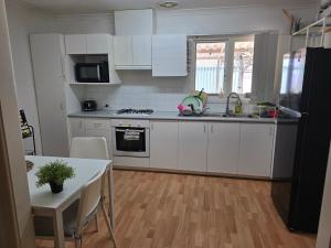 a kitchen with white cabinets and a table and a refrigerator at Girrawheen3 - Room in a Shared House in Perth