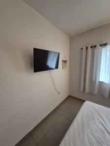 a bedroom with a flat screen tv on the wall at Morada Palmeira Real Peruibe - SP in Peruíbe