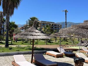 a group of lounge chairs and umbrellas on a beach at Palm Apartments Radhime in Vlorë