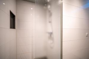 a shower with a glass door in a bathroom at Appartementencomplex Juliana 132 in De Koog