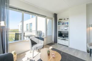 a living room with a large window and a table at Appartementencomplex Juliana 132 in De Koog