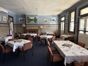 a dining room with white tables and chairs and a fireplace at The Old Vic Hotel in Canowindra