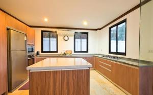 a large kitchen with wooden cabinets and a stainless steel refrigerator at Skyline Seaview Villa-5 Bedroom, 4 Bathrooms with Private Seaview Pool in Ban Thong Phlu