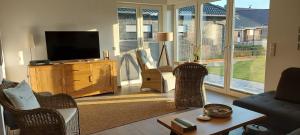 a living room with wicker chairs and a flat screen tv at Haus Admaris am Wangermeer in Wangerland
