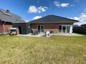 a brick house with a patio and a yard at Haus Admaris am Wangermeer in Wangerland