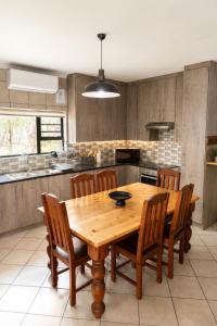a kitchen with a wooden table and wooden chairs at Maningwe in Marloth Park