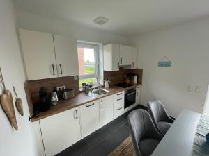 a small kitchen with white cabinets and a sink at Wangerbrise in Wangerland