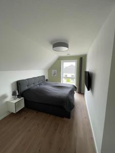 a bedroom with a black bed and a window at Wangerbrise in Wangerland