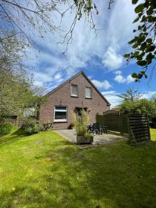 a brick house with a fence in the yard at Bluhm EG in Wangerland
