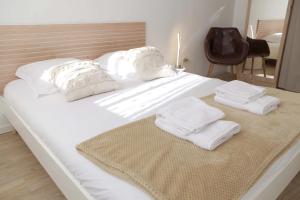 a white bed with towels on it with a chair at Les Coquelicots - Parking privé, Terrasse, Clim, Netflix, Au Calme in Hem-Lenglet