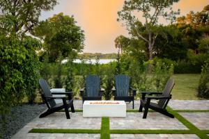 a patio with three chairs and a table with a fire pit at Black Vanilla Luxe Retreat - Sauna, Cold Plunge & Pure Relaxation in Naples