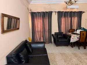 a living room with a black leather couch and a chair at Fitini appart in Bamako