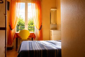 a bedroom with a bed and a window and a table at Hôtel du Nord in Contrexéville
