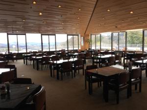 a restaurant with tables and chairs and large windows at Utsunomiya Inter Resort Hotel & Golf Tsuru Country Club in Utsunomiya