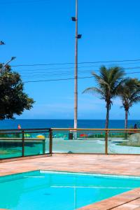 a swimming pool with the ocean in the background at Refugio do Forte Cabo Frio in Cabo Frio