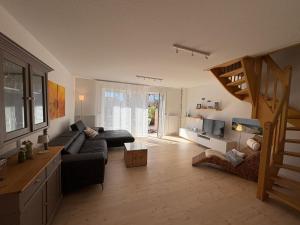 a living room with a couch and a staircase at Haus Strandgut in Hooksiel in Wangerland