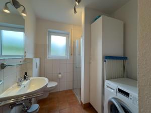 a bathroom with a sink and a washing machine at Haus Strandgut in Hooksiel in Wangerland +24 photos