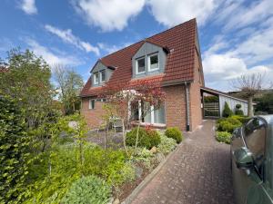 a red brick house with a brick driveway at Haus Strandgut in Hooksiel in Wangerland