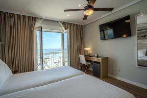 a bedroom with a bed and a desk with a balcony at Hotel Silken Don Pepe y Don Pepe Ría in Ribadesella