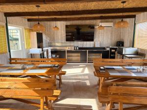 a restaurant with wooden tables and benches and a kitchen at Iberfishing Apartmanok in Caspe