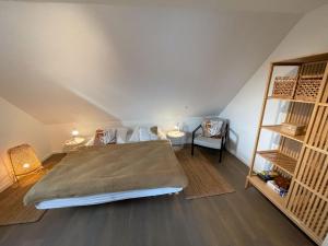 a bedroom with a bed and two chairs in a attic at Steuerbord Nock mit Hund in Wangerland