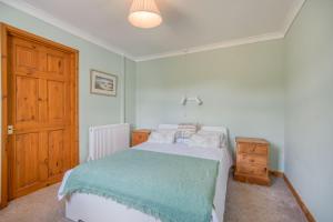 a bedroom with a bed and a wooden door at Heddfan Cottage in Haverfordwest