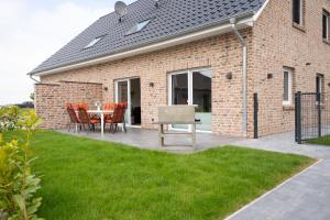 a patio with a table and chairs in front of a brick building at Haus Wanger Meerblick in Wangerland