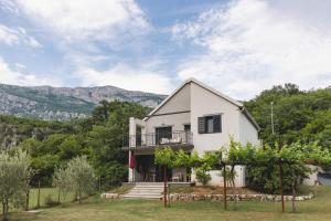 a white house with trees and mountains in the background at Kami The Essence in Danilovgrad
