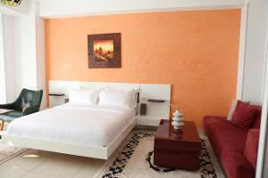 a bedroom with a white bed and a red couch at Prince Adriatic Resort in Shëngjin