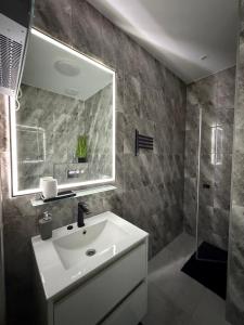 a bathroom with a sink and a mirror and a shower at RVR Apartmanhàz in Sárospatak +5 photos