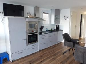 a kitchen with white cabinets and a tv on top at Hausboot MeerZeit in Wangerland