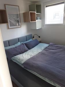 a bedroom with a bed with blue sheets and a window at Hausboot MeerZeit in Wangerland