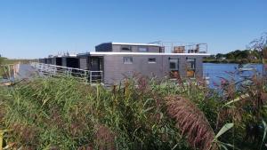 a house on the side of a body of water at Hausboot MeerZeit in Wangerland