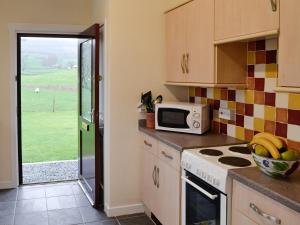 a kitchen with a microwave and a stove top oven at Beuchan Bungalow in Closeburn